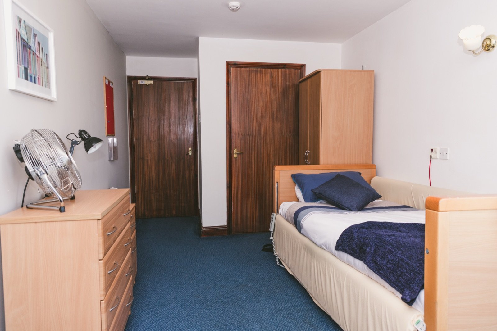 Comfortable resident bedroom with blue curtains and armchair
