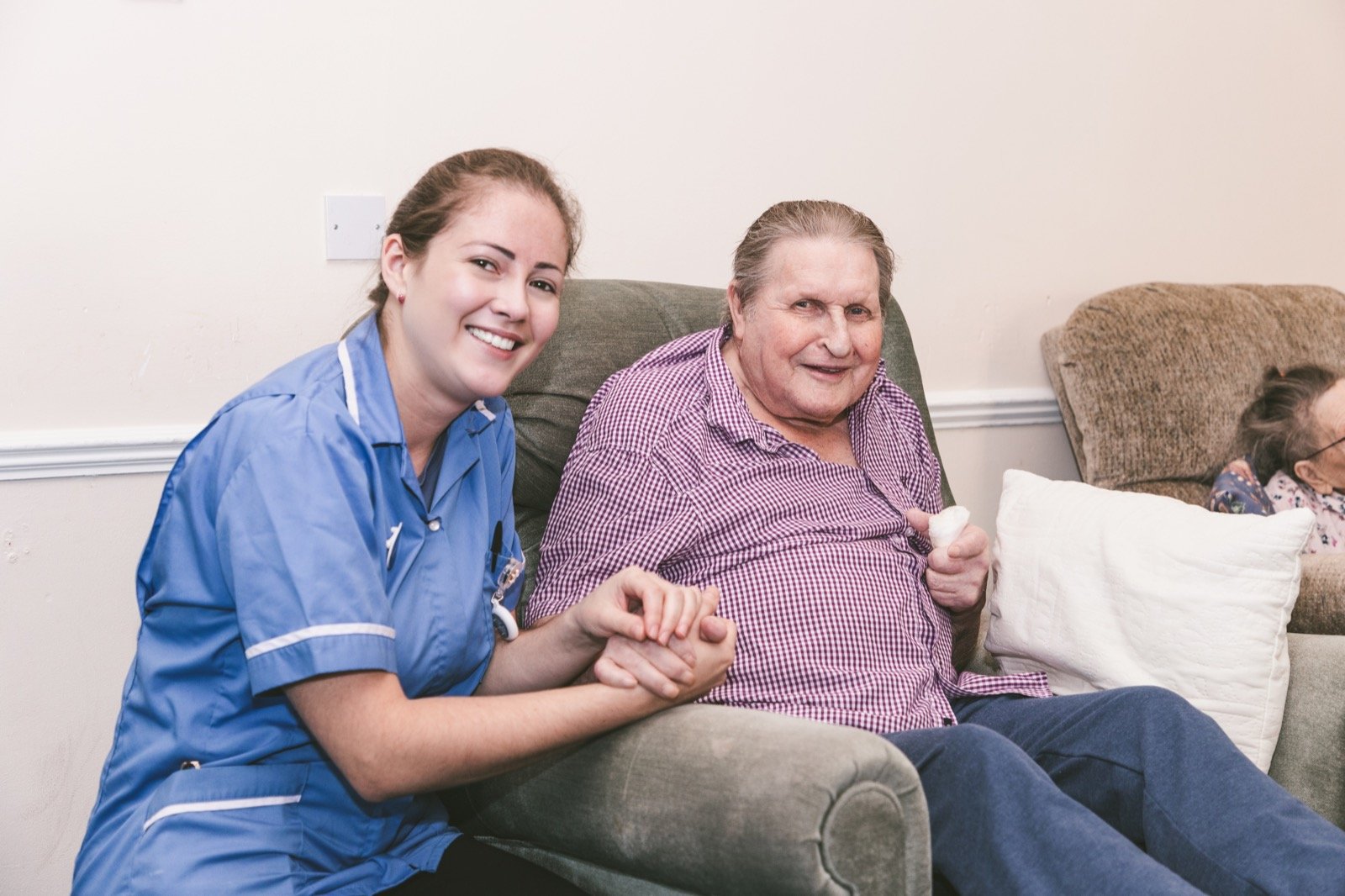 A carer holding hands with a resident, both laughing